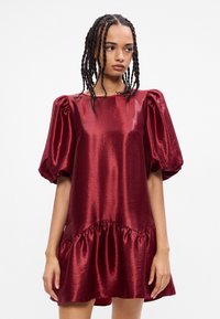 Μπρούντζινο σατέν φόρεμα με φουσκωτά κοντά μανίκια, τετράγωνη λαιμόκοψη και ραμμένο στρίφωμα, με απλή, γυαλιστερή υφή.