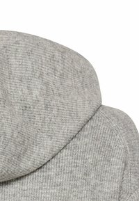 Haut à capuchon gris en tissu doux et texturé. Il présente une capuche arrondie et un design épuré et minimaliste. Sans matériel ni accents visibles.