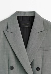 Blazer grigio con motivo a spina di pesce, design doppiopetto, ampie revers, bottoni neri e interno foderato in raso. Etichetta con la scritta "Massimo Dutti."