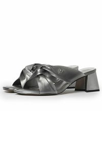 Sandali argentati con design a strisce incrociate, realizzati in materiale metallico lucido. Presentano un tacco a blocco e un'accenno di branding discreto.