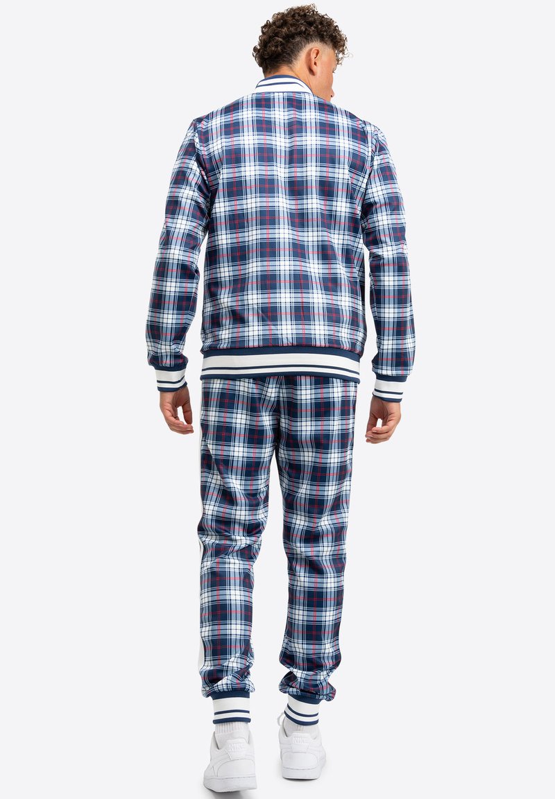 Karierter Trainingsanzug in Marineblau, Rot und Weiß mit gerippten Bündchen und Saum. Die Jacke hat einen kontrastierenden Kragen und einen elastischen Saum.