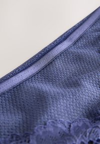 Biancheria intima in tessuto a rete blu scuro con rifinitura in pizzo lungo il bordo inferiore, caratterizzata da una fascia in raso liscia per un maggiore comfort.