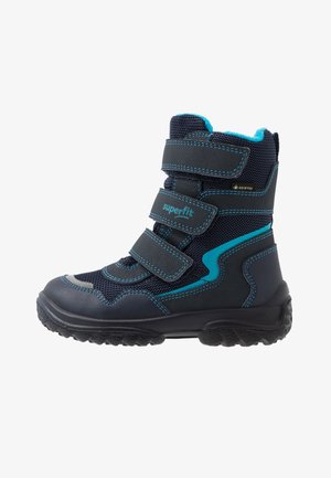 Børns sorte og blå vinterstøvle med tre velcroremme, robust sål, blå syninger og Gore-Tex vandtæt materiale.