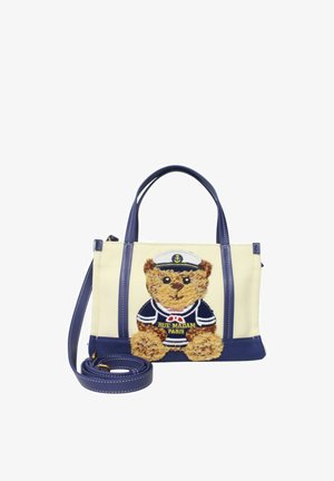 Borsa beige e blu navy con doppie maniglie e un orsetto con indosso un completo da marinaio ricamato sulla parte anteriore, con testo "Rue Madam Paris".