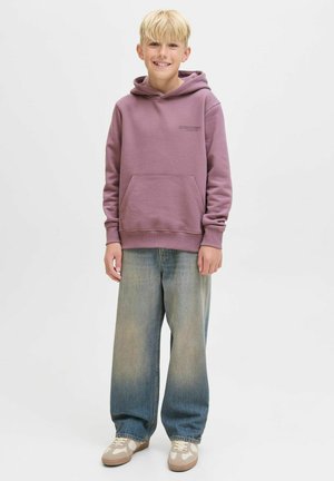 Lila hoodie med känguruficka och logotyp, kombinerad med vida blå jeans och beige sneakers. Slät textur och avslappnad design.