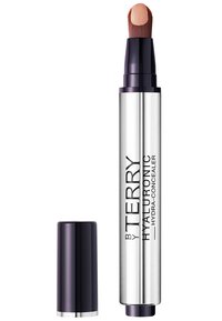 Hyaluronsäure-Concealer in einer silbernen Tube mit einem dunkelvioletten Deckel, ausgestattet mit einer schrägen Bürstenspitze und einem aufgetragenen nudefarbenen Produkt.