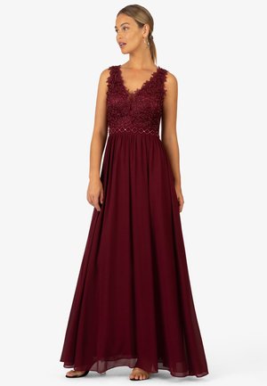 Robe maroon longue avec un décolleté en V, broderies florales délicates au niveau du corsage et une jupe fluide en tissu léger.