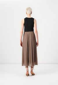 Haut sans manches noir, jupe midi marron avec motif texturé, taille élastique et talons beiges à lanières. Vue arrière simple.