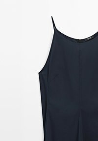 Tmavě modré šaty bez rukávů s tenkými ramínky a jednoduchým, elegantním designem na bílém pozadí.