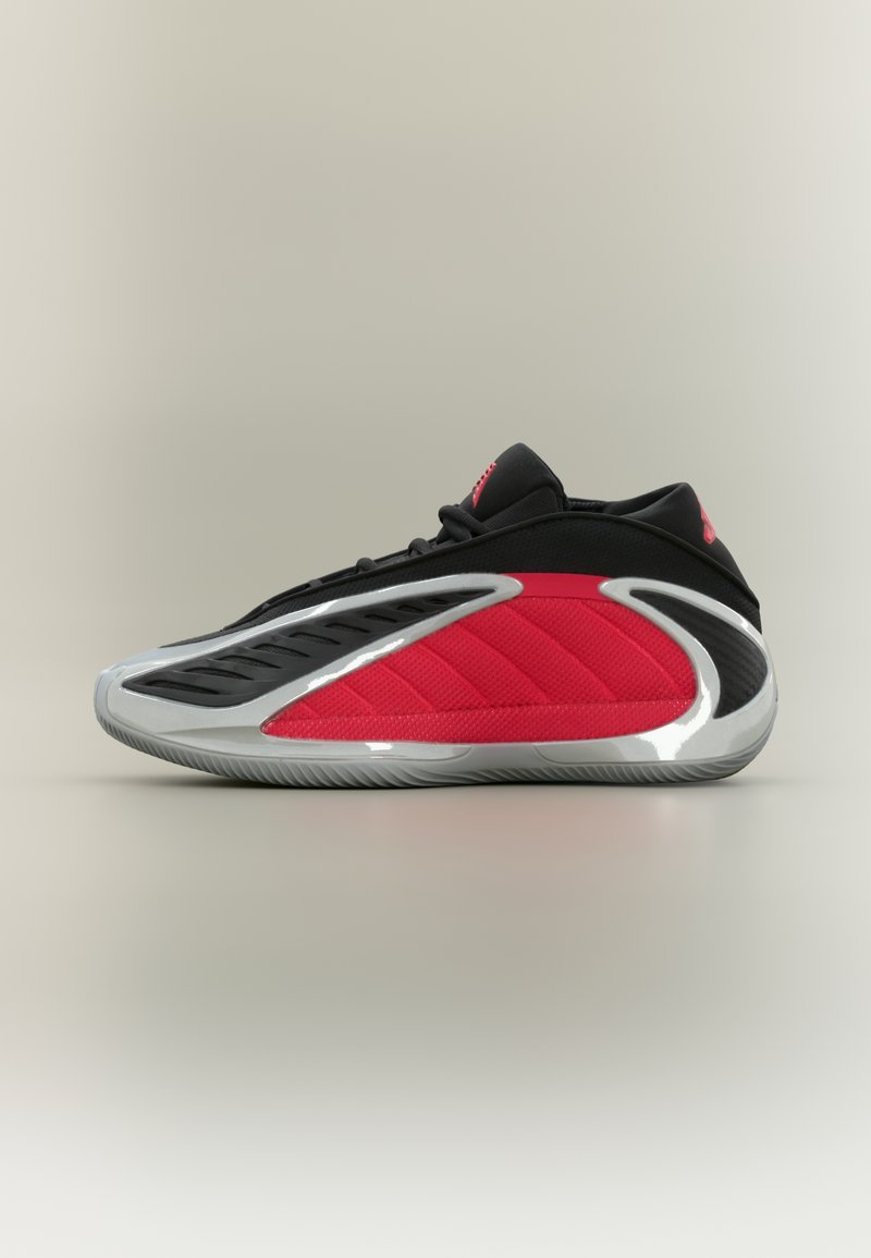 Zapatilla deportiva roja y negra con un diseño aerodinámico, parte superior de malla, panel rojo texturizado y una suela plateada brillante con ranuras.