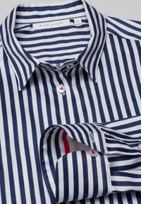 Navy blue and white vertically striped long-sleeve shirt with button-down collar and red-stitched white buttons, laid flat.