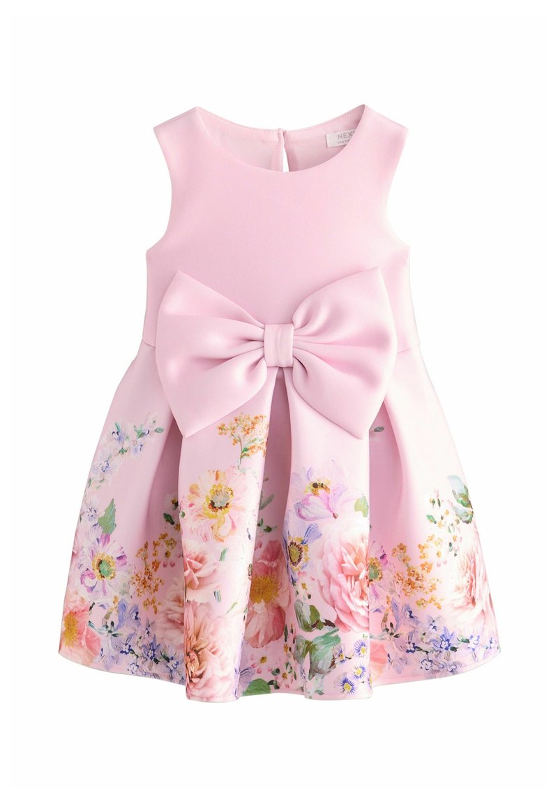 Robe rose sans manches pour fille avec un grand nœud devant et un imprimé floral sur la jupe évasée.