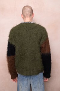 Pleteni pulover z puhasto teksturo, v barvnih blokih zelene, rjave in črne barve. Rebrast rob, prevelik kroj in kratki rokavi.