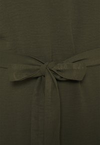 Olivgrön tyg med en mjuk textur, prydd med en knytning i midjan och en slät, flödande design.