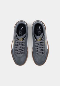 Pelēki sporta apavi ar elegantu dizainu, sintētisks augšdaļa, brūna gumijas zole un pelēkas šņorītes. Ievērojama zelta marka un mīkstināta zole.