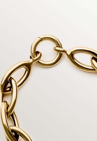 Collar de cadena de metal dorado con eslabones ovalados y un acabado pulido, y un broche circular. Textura suave con un diseño entrelazado.