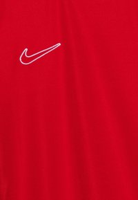 Camiseta roja de Nike hecha de tejido suave; presenta un pequeño logo bordado en blanco en el pecho; mangas cortas y cuello redondo.
