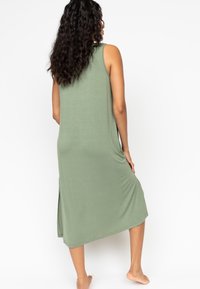 Robe midi sans manches en vert olive, fabriquée en tissu doux et extensible. Avec des fentes sur les côtés pour faciliter les mouvements et une coupe décontractée.