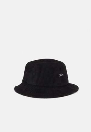Bob en velours côtelé noir avec tissu texturé, couronne ronde et large bord incliné vers le bas. Présente "OBEY" brodé en blanc.