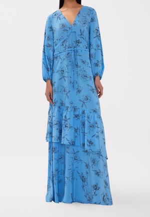 Frau trägt ein langes, himmelblaues Kleid mit Blumemuster, V-Ausschnitt, langen Ärmeln, Taillengürtel und mehrlagigem Volantrock, steht vor einem schlichten Hintergrund.