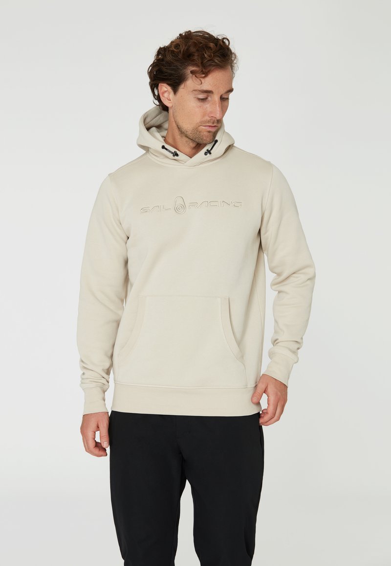Sudadera beige hecha de tejido suave, con un bolsillo frontal, capucha con cordones y logo grabado de "SAIL RACING" en el pecho.