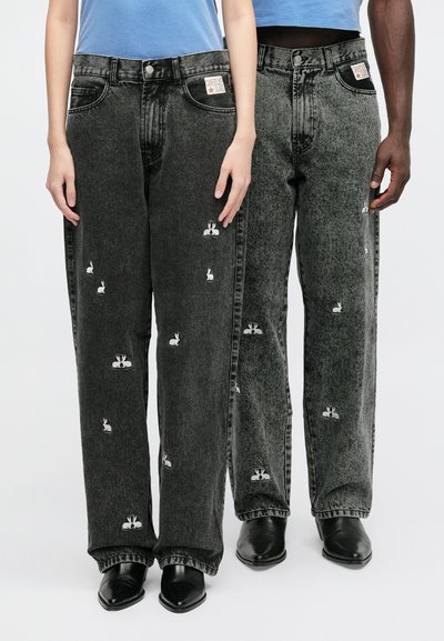 Svarta jeans i denim med lös passform, broderade kaninmotiv, fem fickor och en avsliten kant. Kombinerade med spetsiga svarta skor.