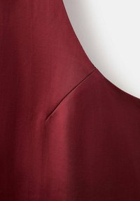 Top sin mangas color burdeos con una textura suave, que presenta un sutil detalle de costura y un discreto bolsillo lateral.