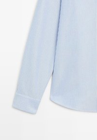 Camicia a maniche lunghe a righe blu chiaro realizzata in tessuto morbido, con polsini abbottonati e un design del colletto classico.