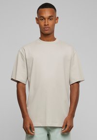 Beige t-shirt med korte ærmer lavet af blødt stof. Crew neck design med en afslappet pasform, der har en glat tekstur og oprullede ærmer.