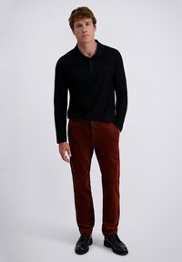 Black long-sleeve polo shirt paired with brown corduroy pants. Black lace-up shoes, fitted silhouette, smooth texture, and subtle design details.