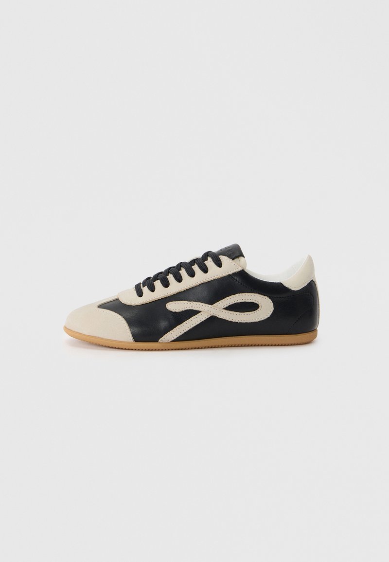 Sneaker in pelle nera e beige con punta arrotondata, design con lacci e un accento distintivo del logo. Suola in gomma offre una maggiore aderenza.