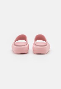 Scarpe slip-on rosa con tomaia testurizzata, apertura sul retro e suola piatta. Bordo liscio e arrotondato, progettate per il comfort e la facilità d'uso.