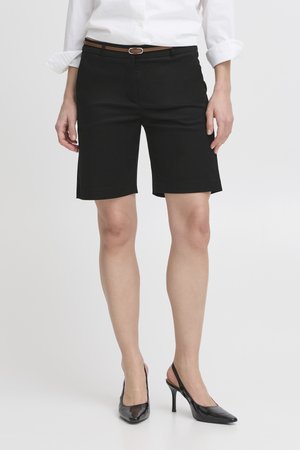 Valge pika varrukaga särk, mis on pandud mustade, põlvepikkuste pükste sisse, pruuni vööga, koos mustade slingback-kontsadega.