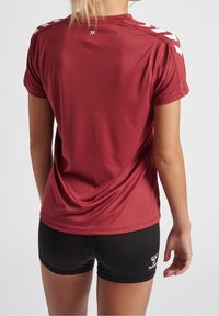 Camisa atlética de manga corta en color burdeos con rayas de acento blancas en los hombros. Tela ligera y suave con escote redondo y corte relajado.