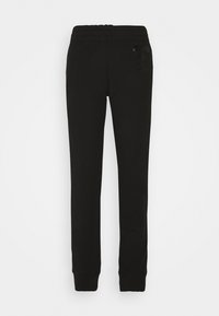 Svarta sweatpants med elastisk midja, avsmalnande ben och en diskret logodetalj på sidan. Tillverkade av mjukt bomullstyg.