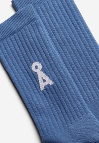 Blaue gerippte Socken mit einem weißen gestrickten Buchstaben "A"-Logo. Weicher Stoff und klassisches Design, geeignet für die Freizeit.