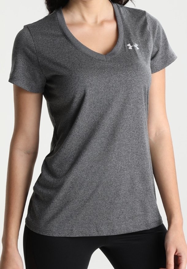 Femme portant un t-shirt de sport ajusté à manches courtes gris foncé avec un petit logo blanc sur le haut de la poitrine.