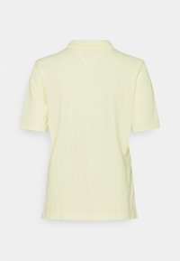 Polo a maniche corte in morbido tessuto giallo pastello con colletto classico e una finitura testurizzata sottile sul retro.
