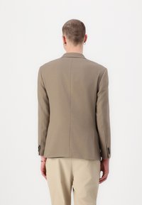 Brown blazer made of woven fabric, featuring a single vent at the back, long sleeves, and black button accents at the cuffs.