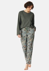 Långärmad olivgrön topp i kombination med ljusblå pyjamasbyxor med blommönster i orange, beige och mörkblå nyanser.