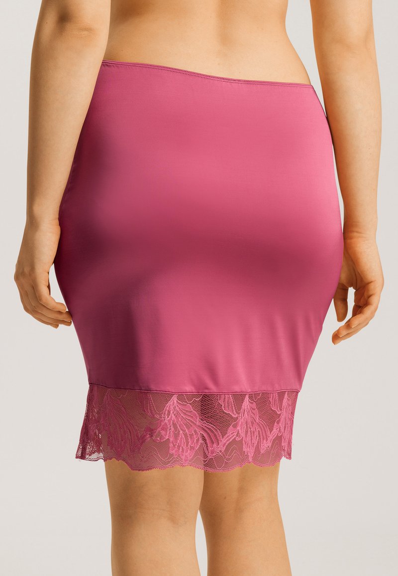 Falda ajustada de satén magenta con un dobladillo de encaje, que presenta un patrón floral y bordes festoneados.