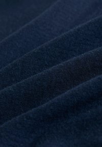Navyblauer Stoff mit weicher Textur, sichtbar gewebtem Muster und geschichteten Falten. Die Oberfläche wirkt leicht flauschig.
