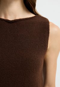 Bruine mouwloze top van textuurgebreid stof. Kenmerkt zich door een subtiele, brede halslijn en een schoon, minimalistisch ontwerp zonder patronen.