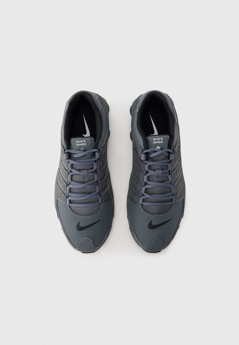Nike Shox shoes in dark gray with a textured upper, lace-up closure, visible branding, and a distinctive sole design.