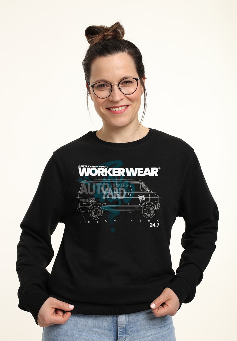 Svart sweatshirt med grafiskt tryck av en van, "WORKER WEAR," och textinslag. Mjuk tyg med rund hals och långa ärmar.