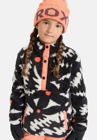 Czarno-biały polarowy pulower z abstrakcyjnymi wzorami i pomarańczowym zamkiem. Posiada wysoki kołnierz, czarne guziki i pomarańczową kieszeń.