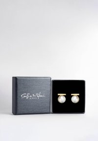 Gemelli in perla con accentuazione in oro, contenuti in una scatola nera testurizzata. Presentano una superficie liscia e rotonda e un design geometrico semplice.