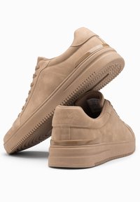 Beige mokasiner av semsket skinn med en jevn tekstur, rund tå og minimalistisk design. Har en gjennomsiktig detalj på hælen og en mønstrete såle.