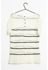 Top en dentelle à manches courtes, base crème, ornée de rayures noires horizontales et de boutons ronds noirs le long du dos. Texture légère.