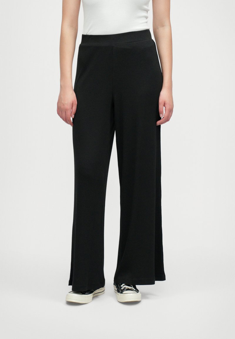Črne široke hlače iz mehkega materiala z elastičnim pasom. Oblikovanje je prostorno, kar zagotavlja udobje in svobodo gibanja.